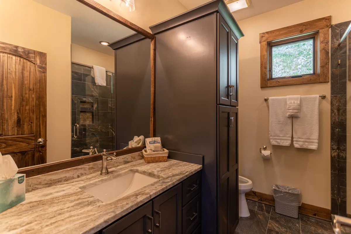 A close-up of a granite countertop paired with dark cabinetry and wooden accents, bathed in morning light. The carefully styled surface and elegant materials highlight the sophisticated touches that elevate the kitchen's design.